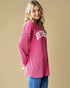 Woman wearing a pink sweater with 'BEVERLY' text on a beige background