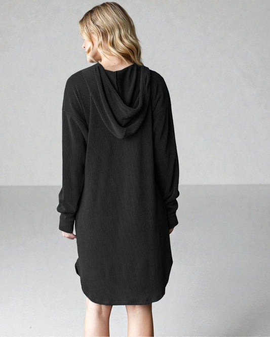Person wearing a black hooded dress against a plain background