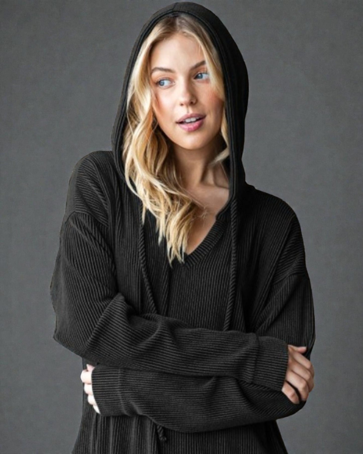 Woman wearing a black hoodie against a gray background