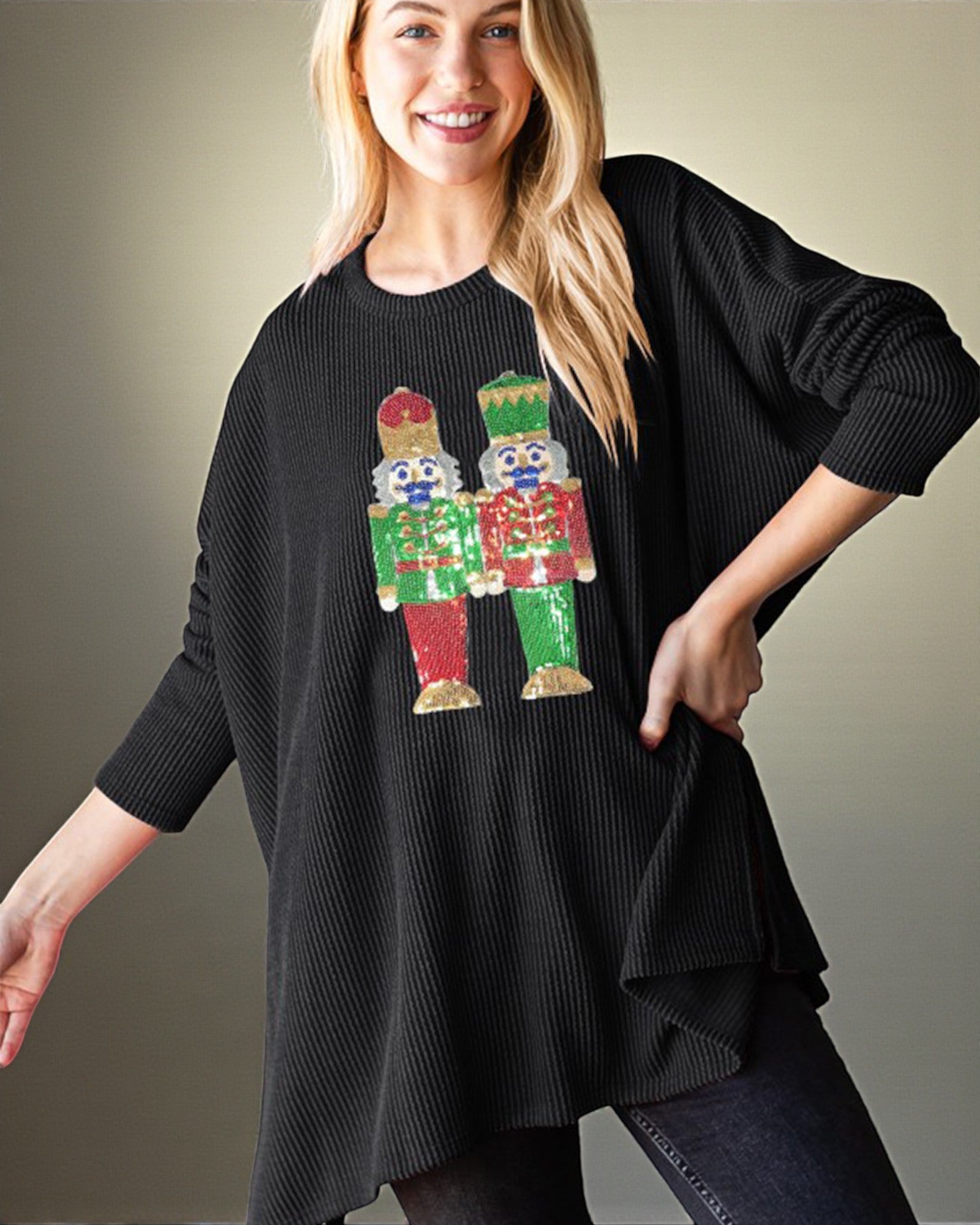 Woman wearing a black sweater with colorful nutcracker design on a plain background