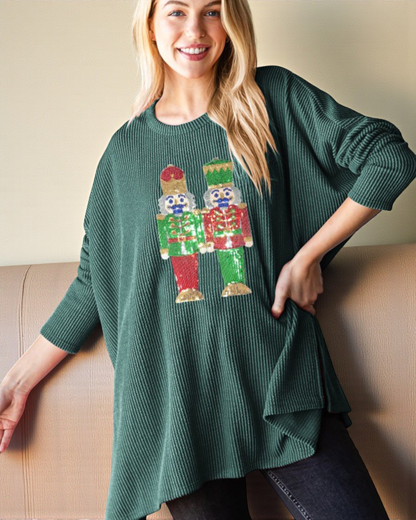 Woman wearing a green sweater with a colorful graphic design, sitting on a beige couch.