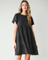 Woman wearing a black tiered dress against a plain background