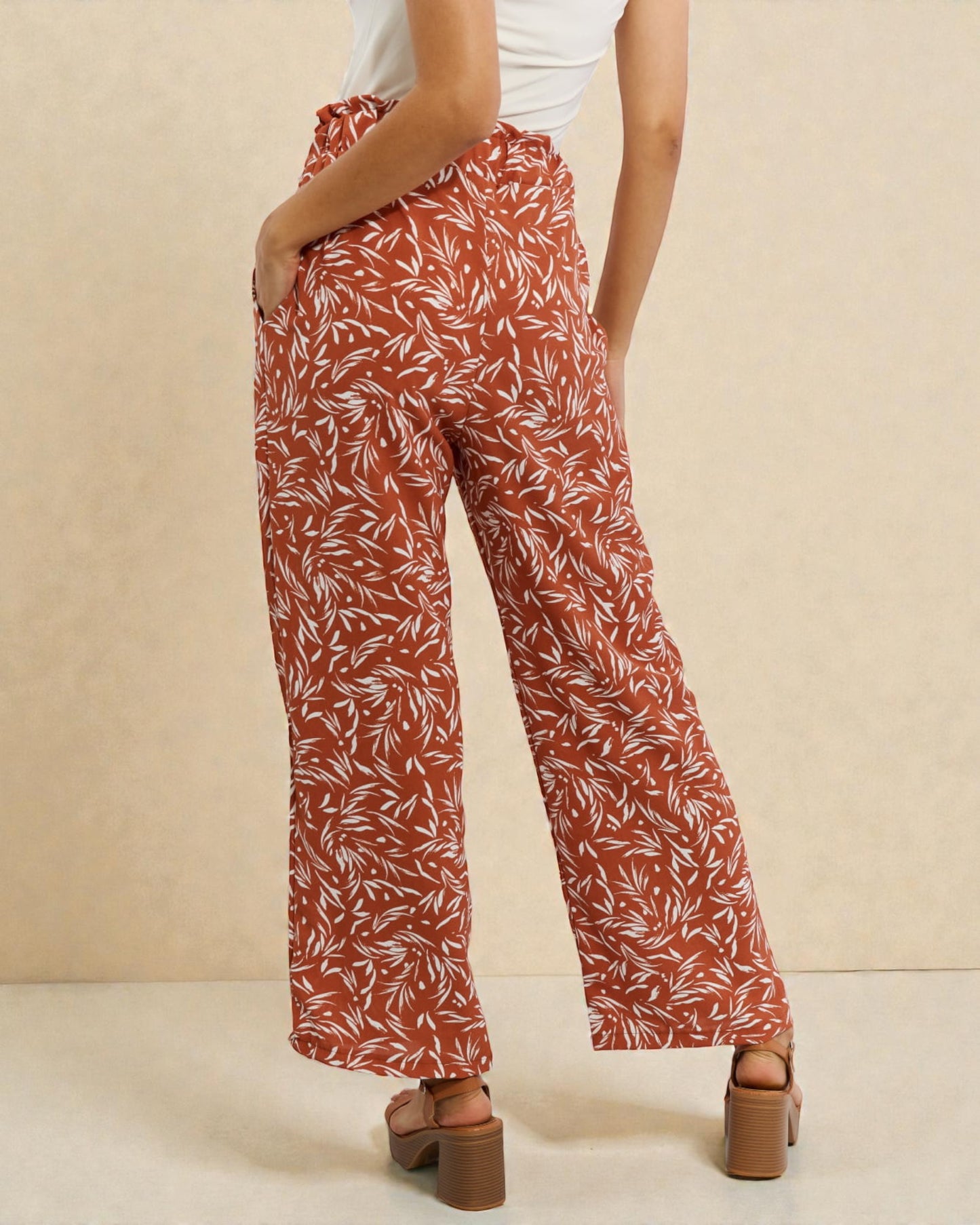 Person wearing rust-colored patterned pants on a beige background