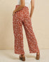 Person wearing rust-colored patterned pants on a beige background