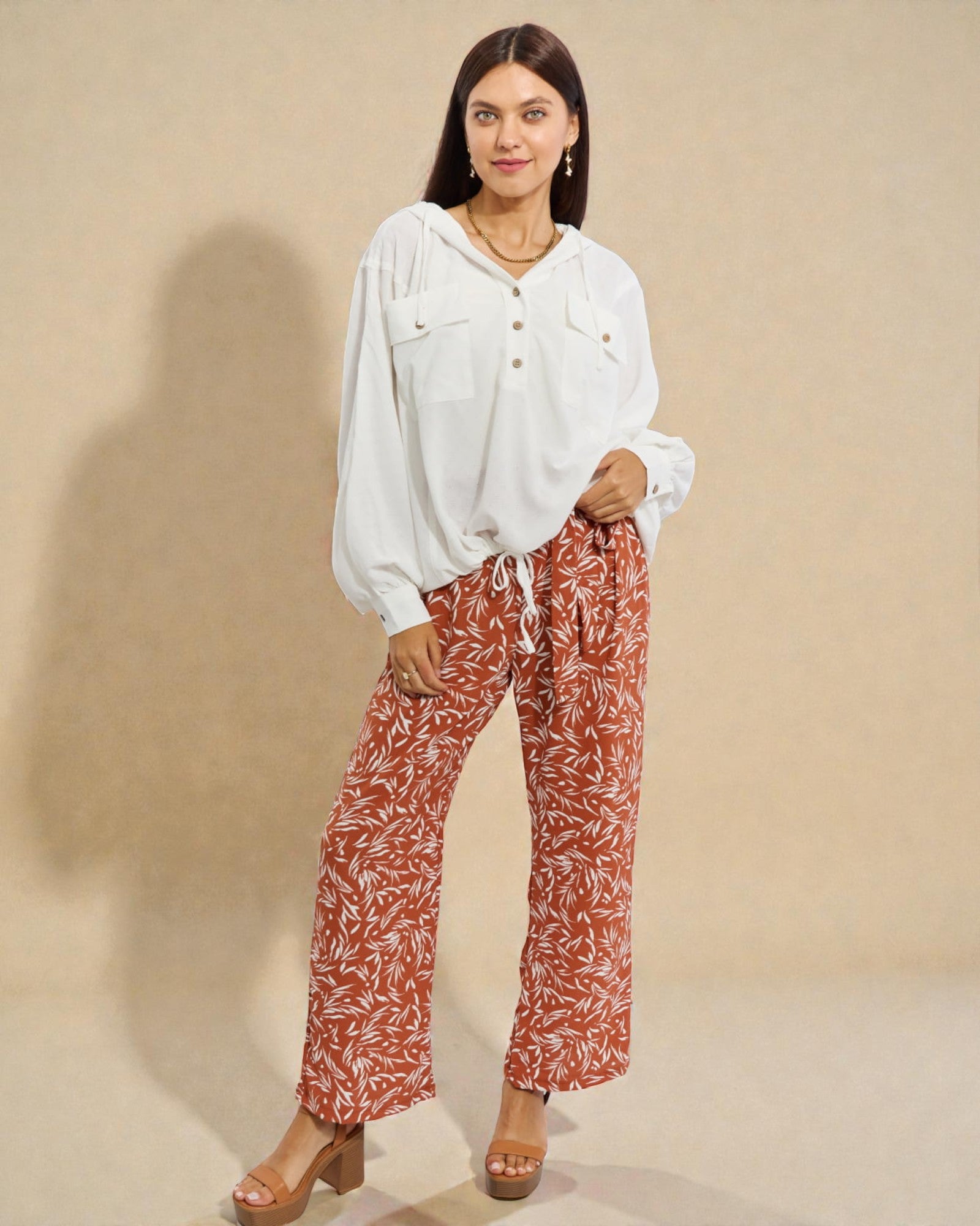 Woman wearing a white shirt and red patterned pants on a beige background
