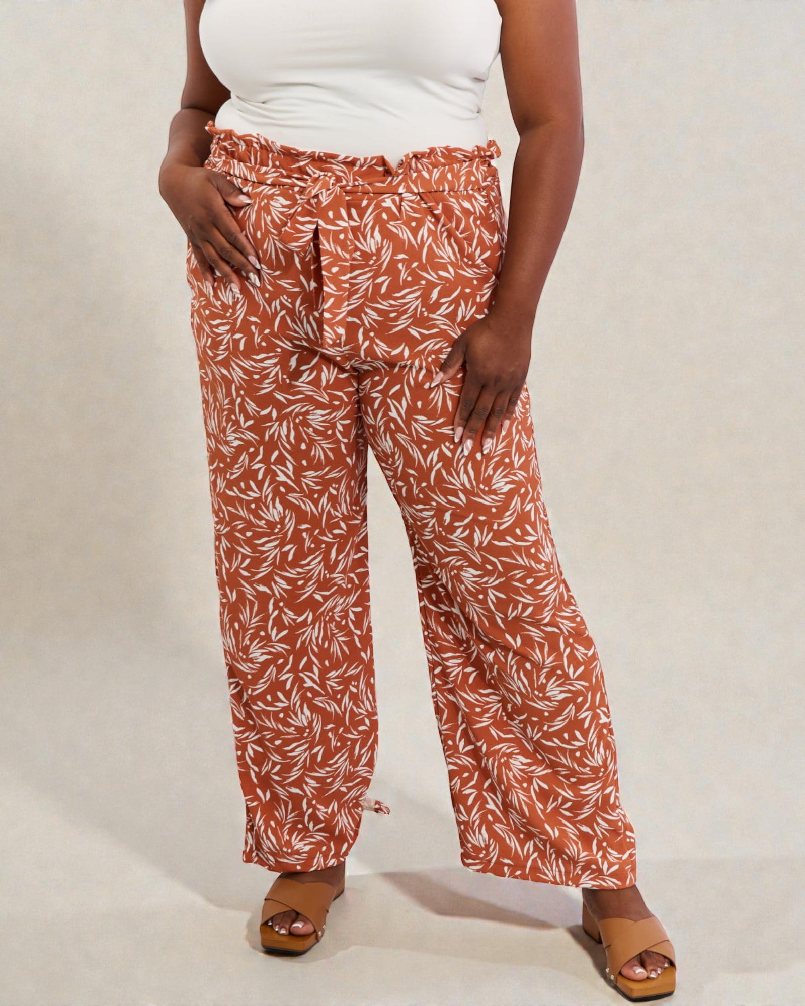 Person wearing rust-colored pants with a white leaf pattern on a plain background