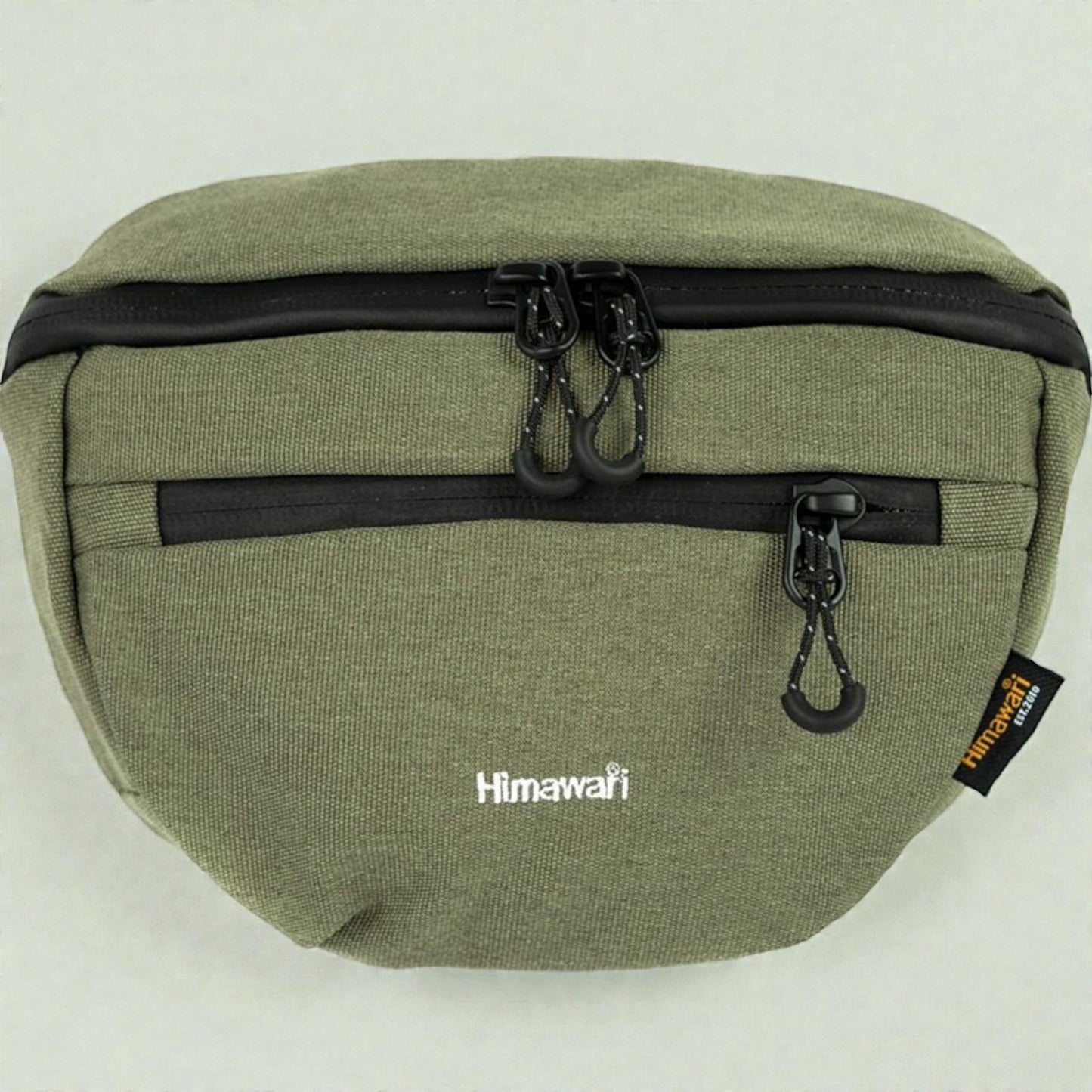Green waist bag with black zippers and a visible brand tag on a white background