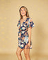 Woman wearing a floral romper against a beige background