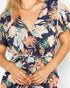 Woman wearing a navy blue dress with colorful floral pattern on a plain background