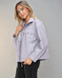 Woman wearing a light purple jacket against a gray background