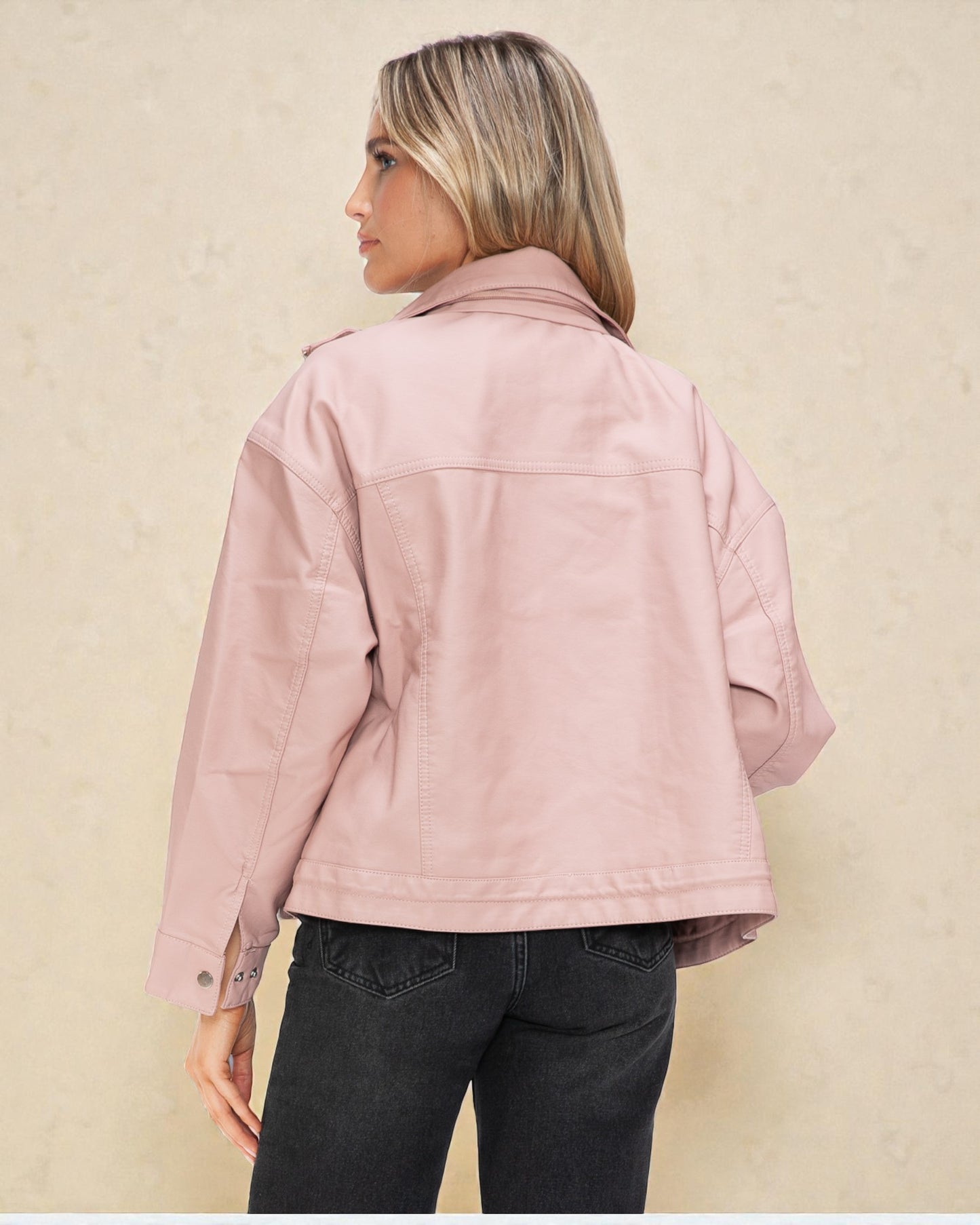 Person wearing a pink jacket and black pants on a beige background
