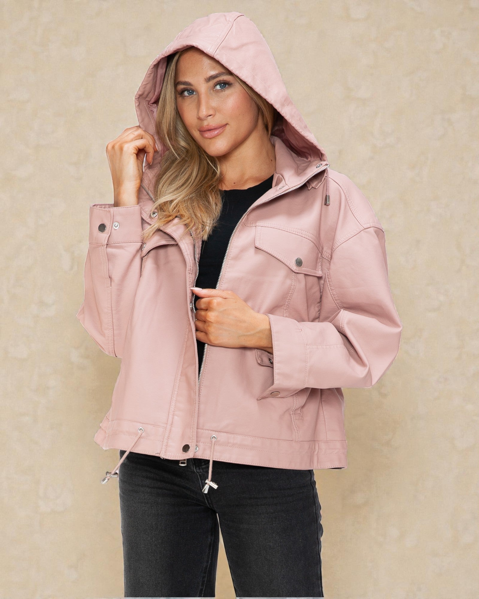 Woman wearing a pink jacket with a hood against a beige background