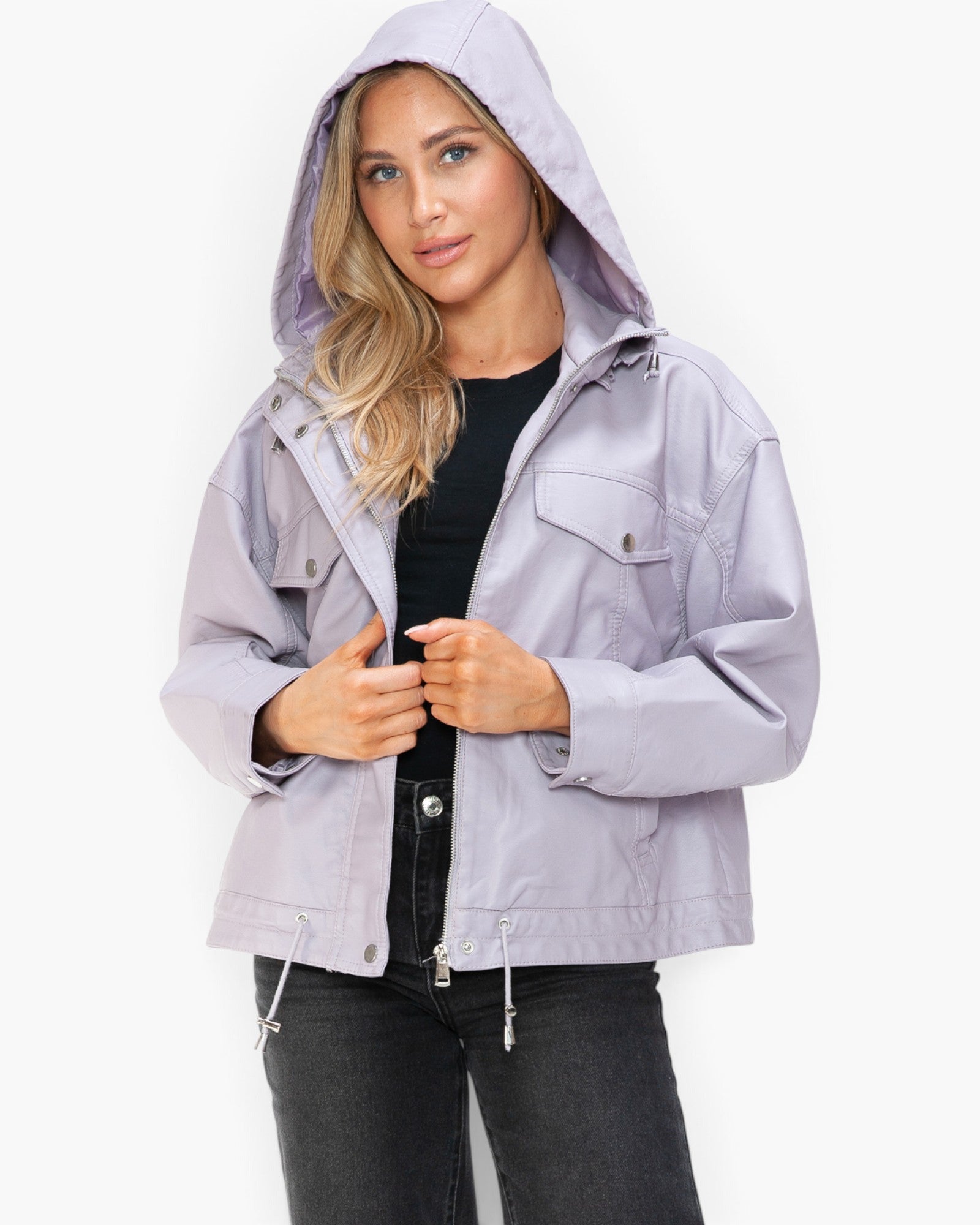 A woman wearing a light lavender hooded utility jacket over a black top and black jeans, standing against a plain white studio background.