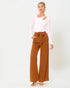 Woman wearing a white long-sleeve top and brown wide-leg pants on a white background