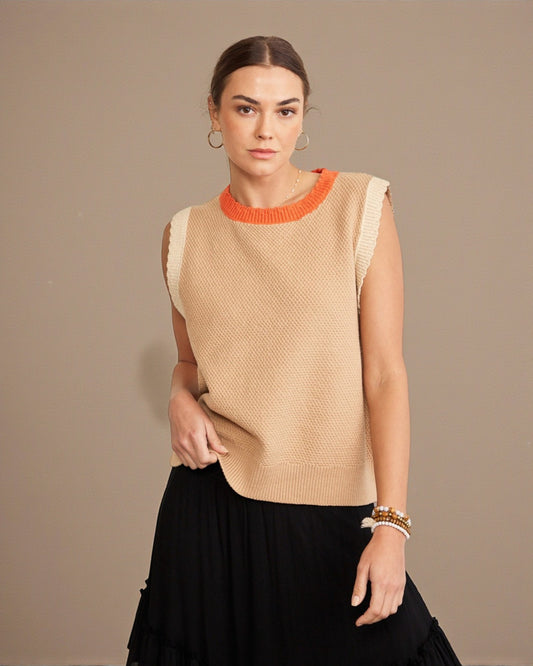 Woman wearing a beige sleeveless top with an orange neckline against a beige background