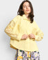 Woman wearing a yellow shirt with lace sleeves against a white background