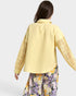 Woman wearing a yellow embroidered jacket with floral pants on a white background