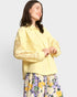 Woman wearing a yellow outfit with floral pants on a light gray background