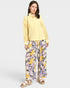 Woman wearing a yellow lace top and floral pants on a white background