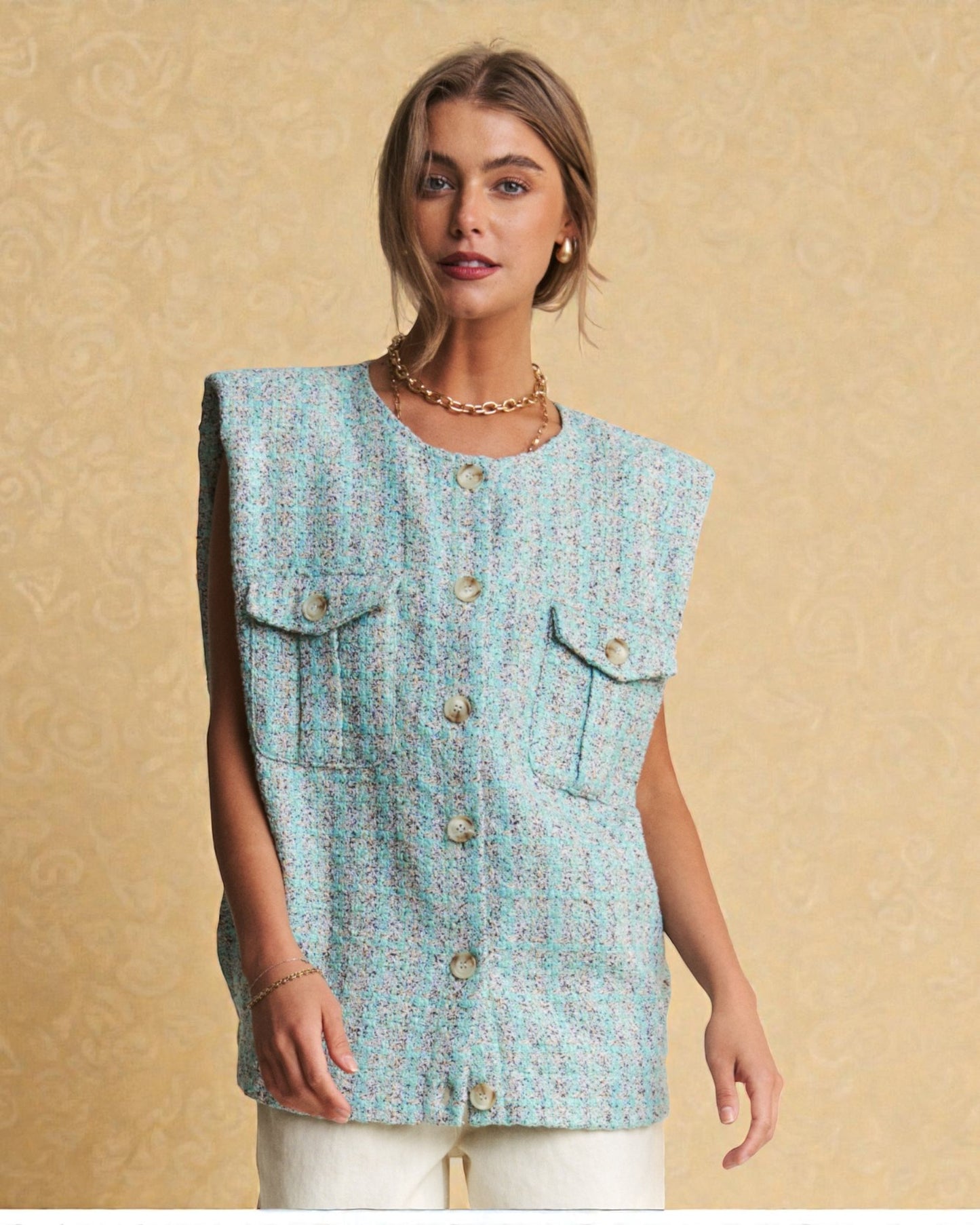 Woman wearing a light blue sleeveless top with buttons on a beige background