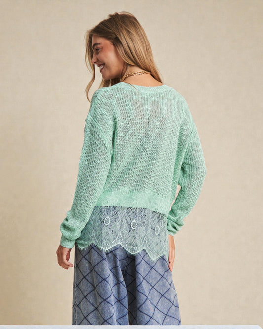 Woman wearing a light green sweater with lace details on a beige background