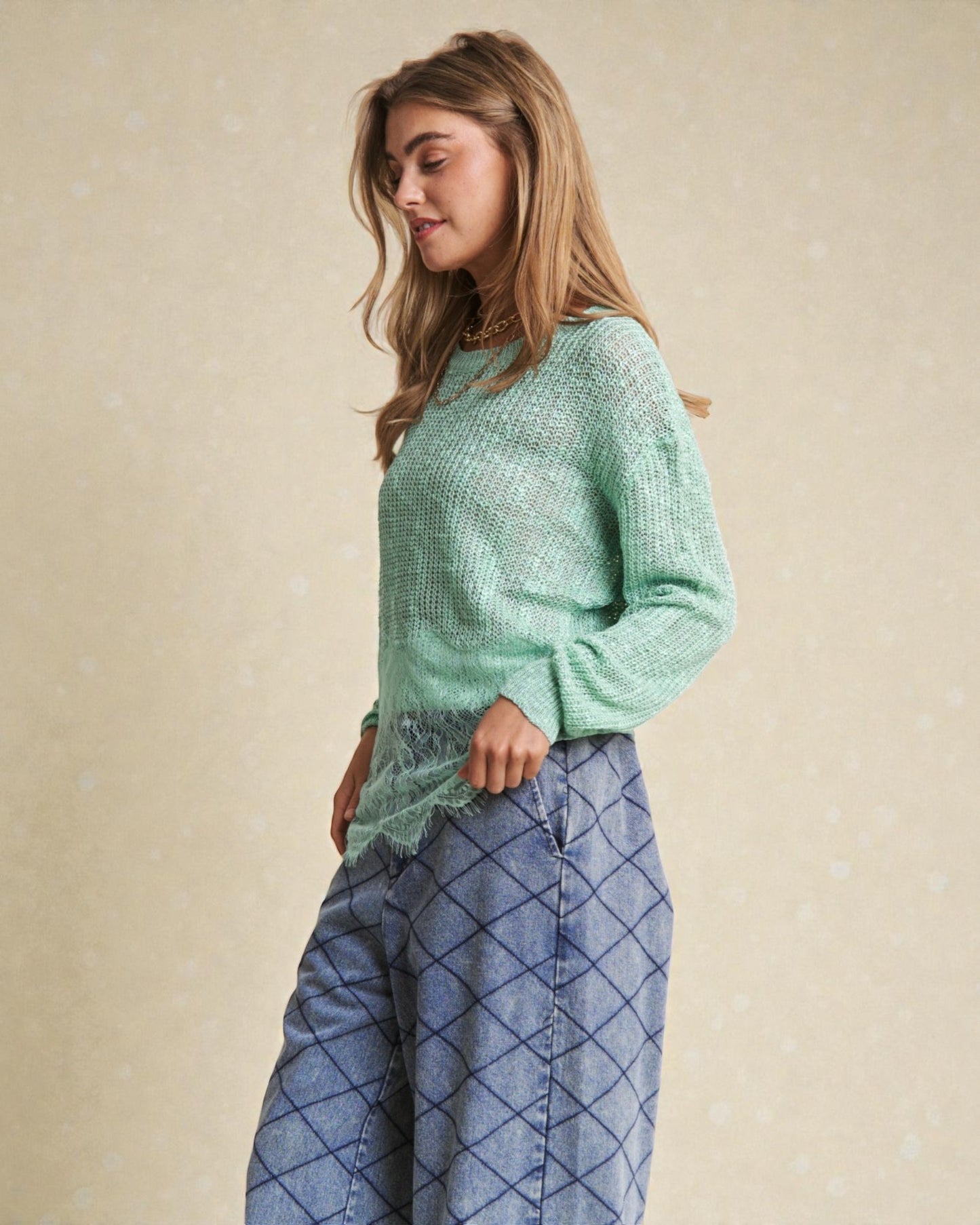 Woman wearing a light green sweater and blue plaid pants against a beige background