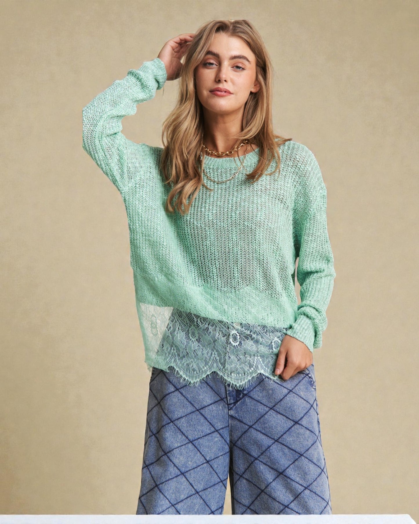 Woman wearing a light green sweater and blue plaid pants against a beige background