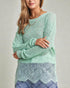 Woman wearing a light green sweater with lace details on a plain background