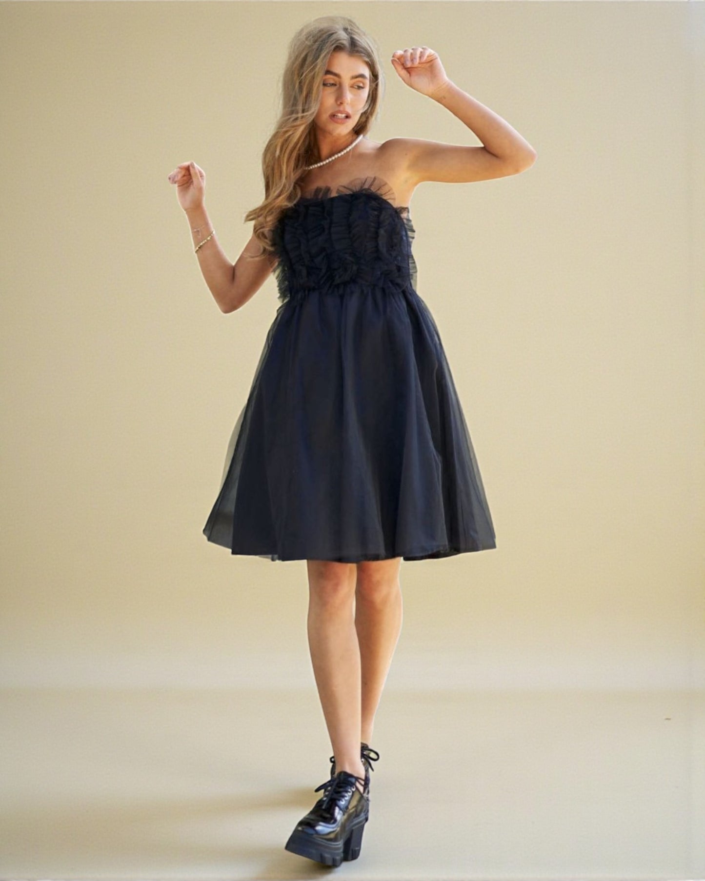Woman wearing a black strapless dress with floral details on a beige background