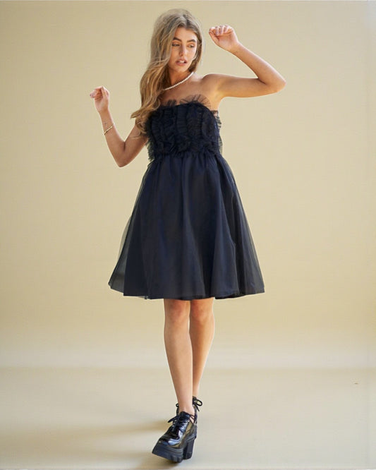 Woman wearing a black strapless dress with floral details on a beige background