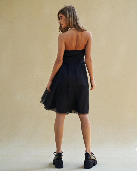 Woman wearing a black strapless dress against a beige background