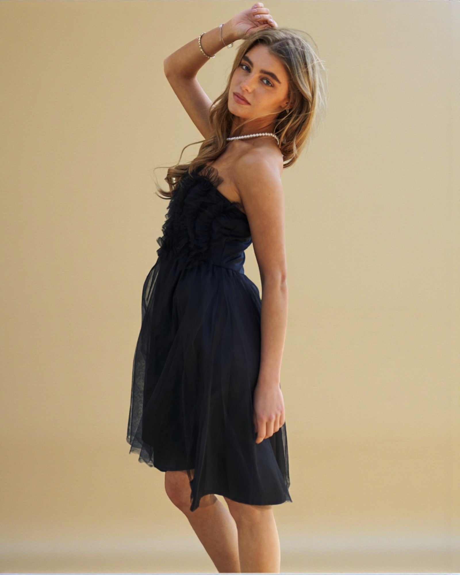 Woman wearing a black dress with floral details against a beige background