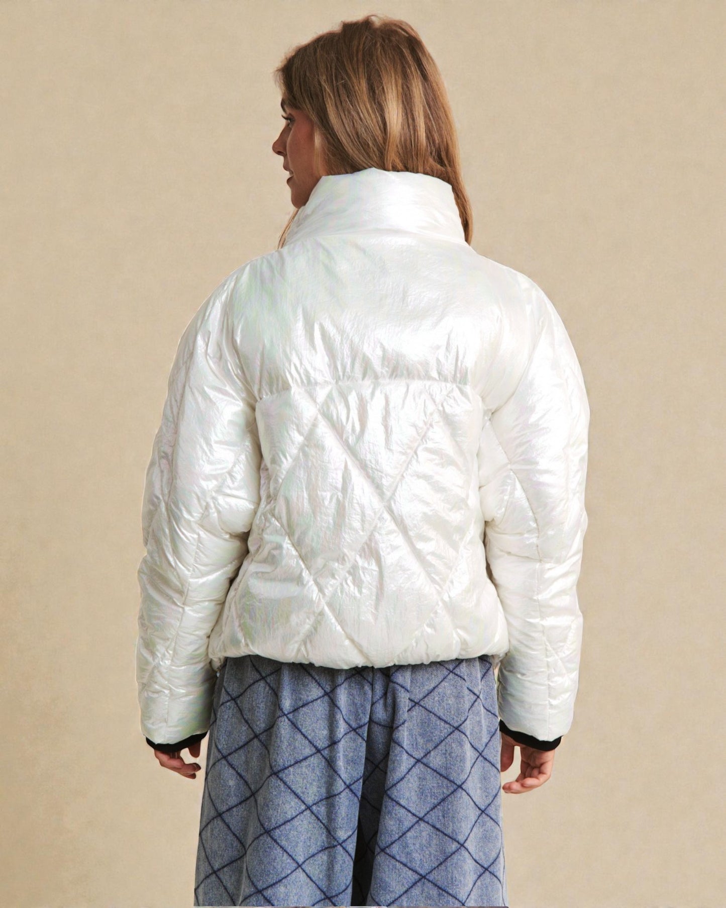 Person wearing a white puffer jacket on a beige background