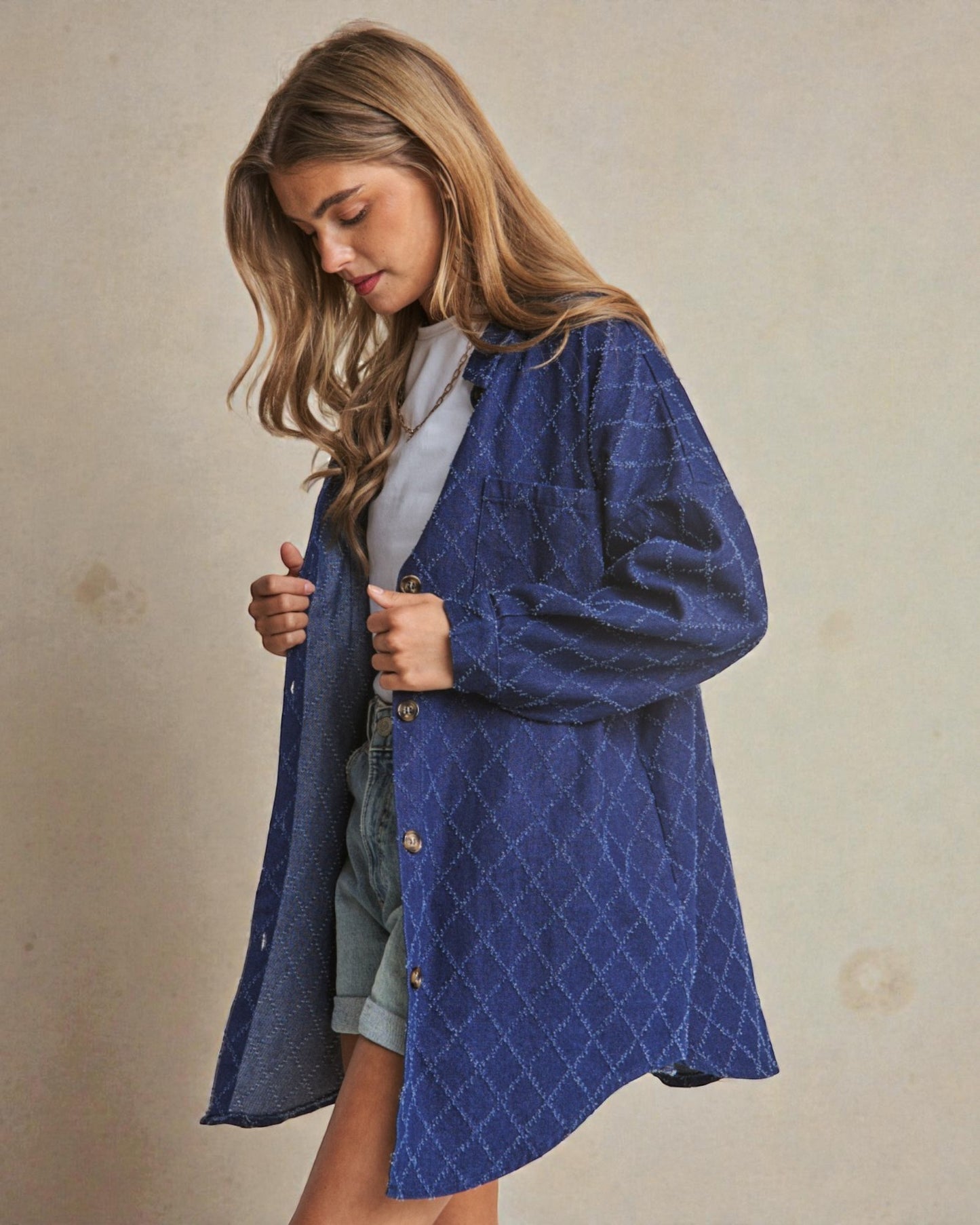 Woman wearing a blue quilted coat against a beige background