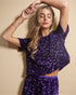 Woman wearing a purple sequin outfit against a beige background