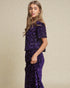Woman wearing a purple sequin outfit against a beige background