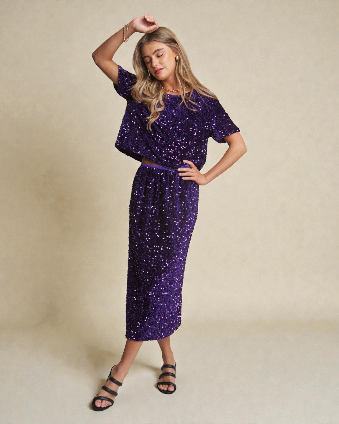 Woman wearing a purple sequin outfit on a beige background