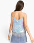 A woman shown from the back wearing a light blue iridescent sequin camisole top with silver fringe and a denim skirt against a plain white background.