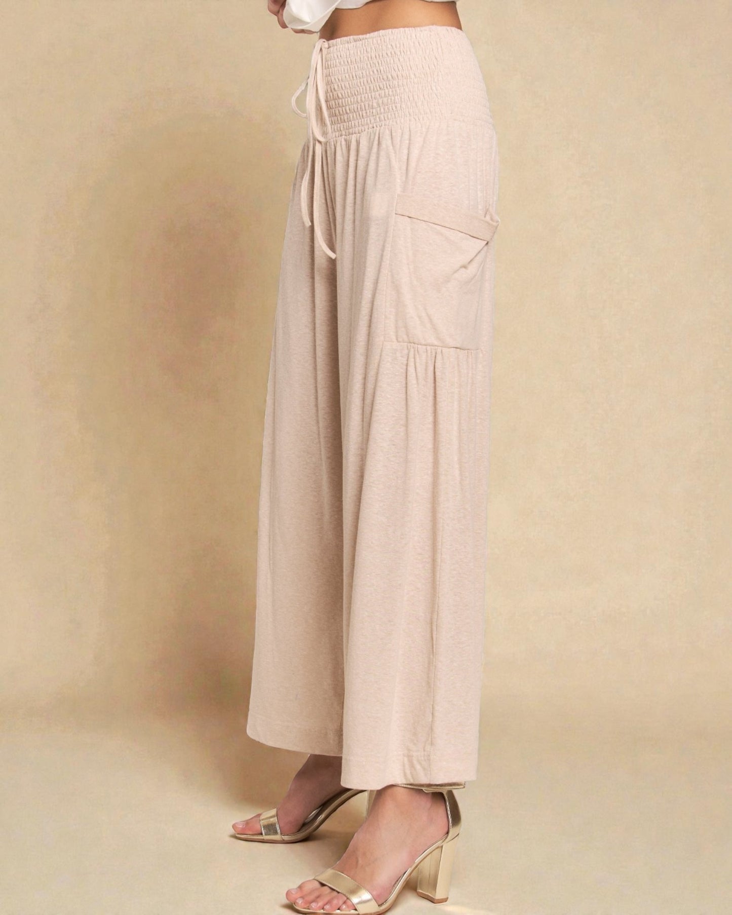 Beige wide-leg pants worn by a person on a beige background