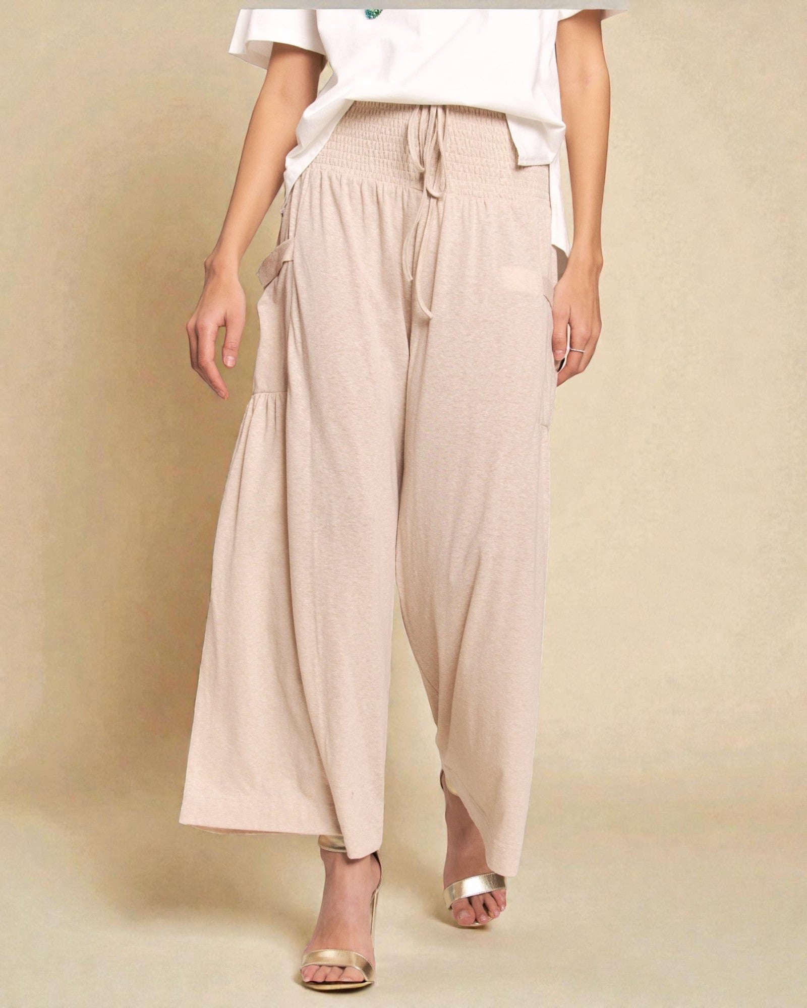 Person wearing beige wide-leg pants on a beige background