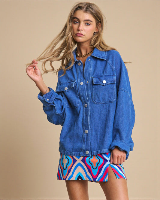 Woman wearing a blue denim jacket and colorful skirt against a beige background