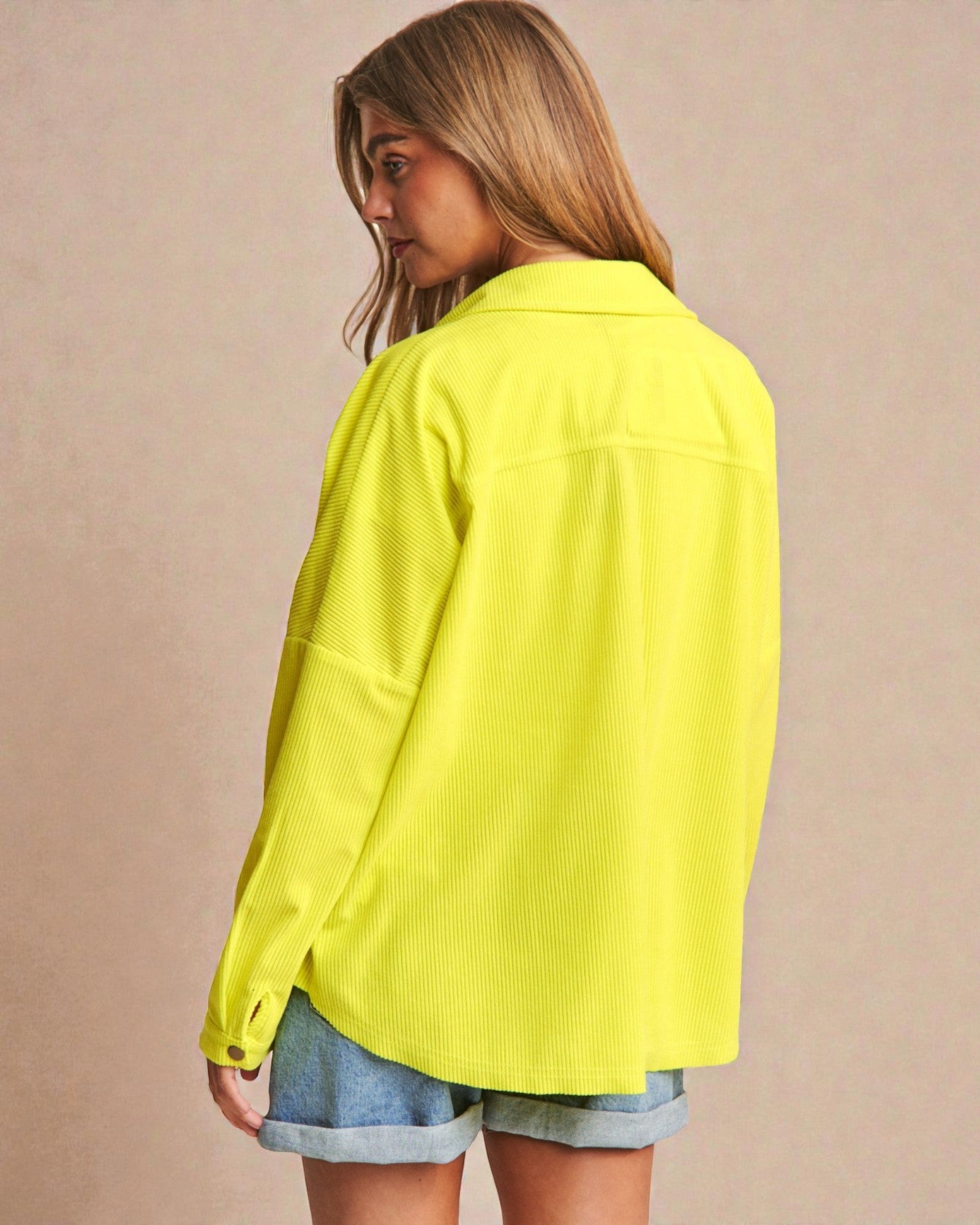 Woman wearing a bright yellow jacket on a beige background