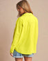 Woman wearing a bright yellow jacket on a beige background