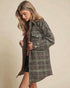 Woman wearing a plaid coat against a beige background