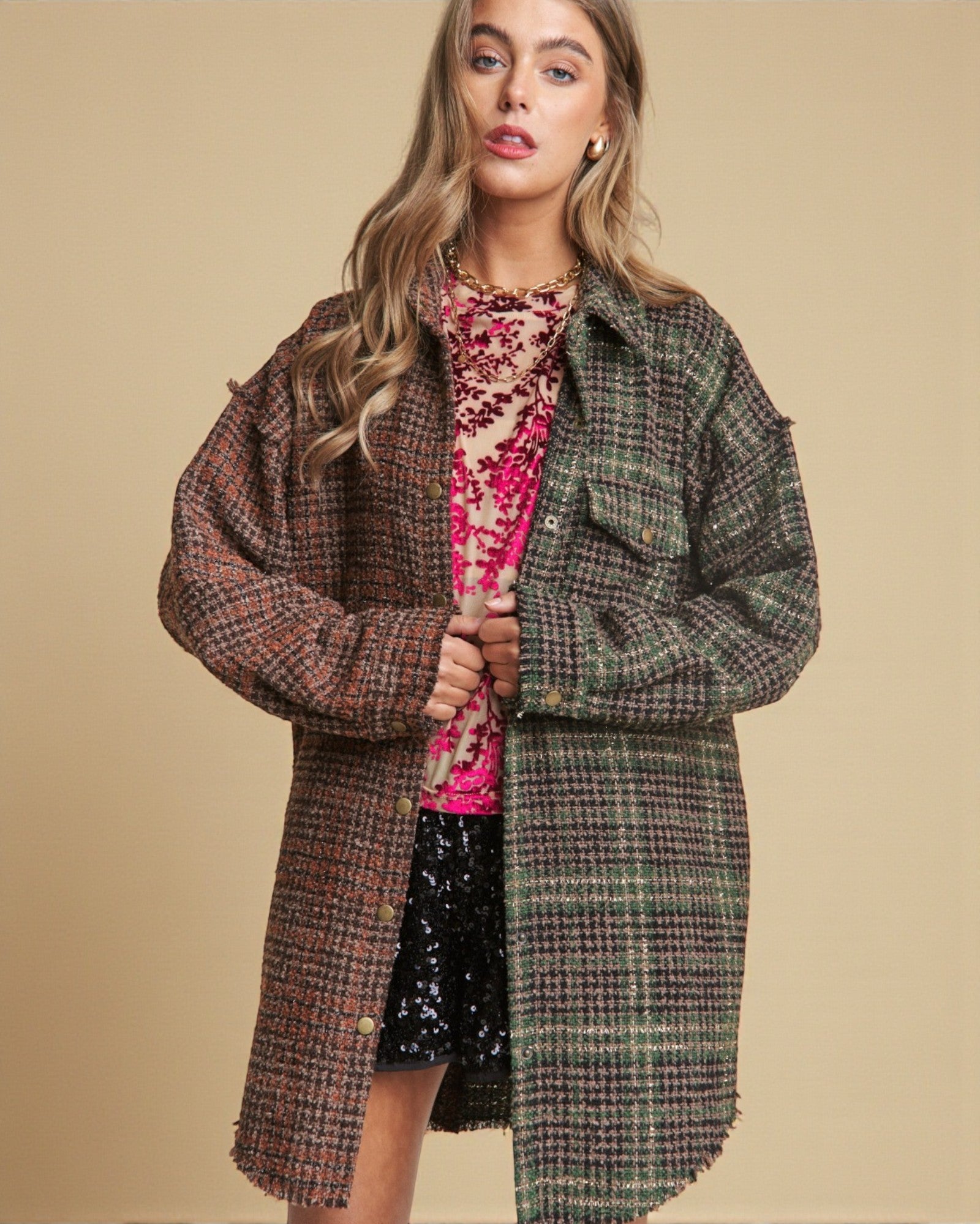 Woman wearing a plaid coat over a colorful dress on a beige background
