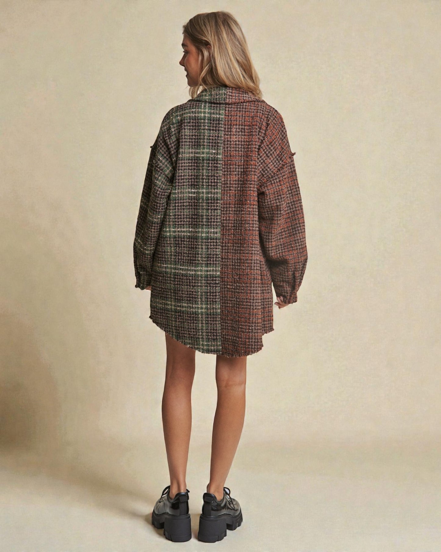 Person wearing a plaid shirt dress with a neutral background