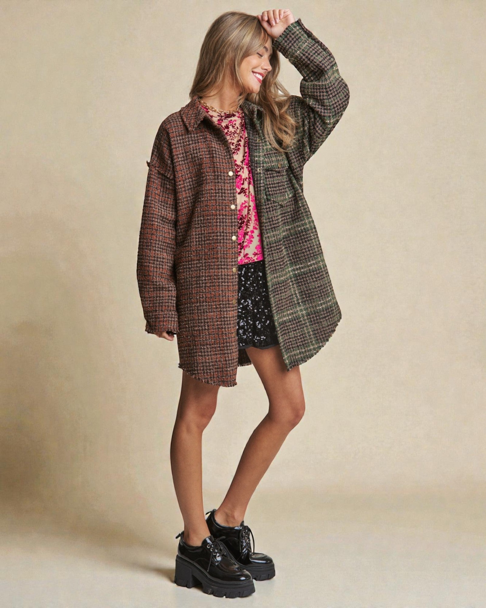 Woman wearing a plaid coat over a floral dress with a beige background