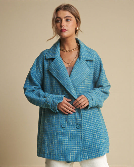 Woman wearing a blue checkered coat against a beige background