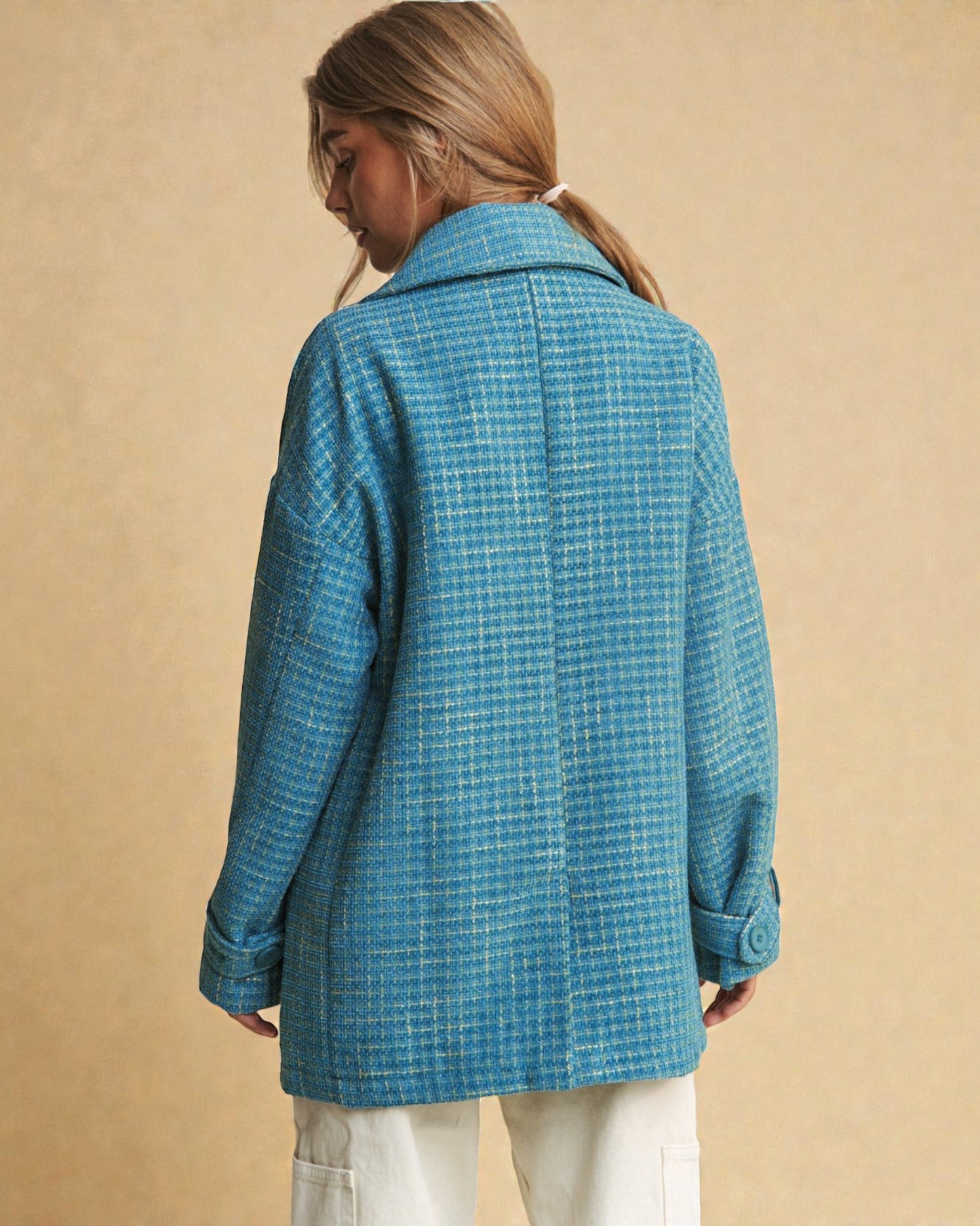 Person wearing a blue checkered coat against a beige background