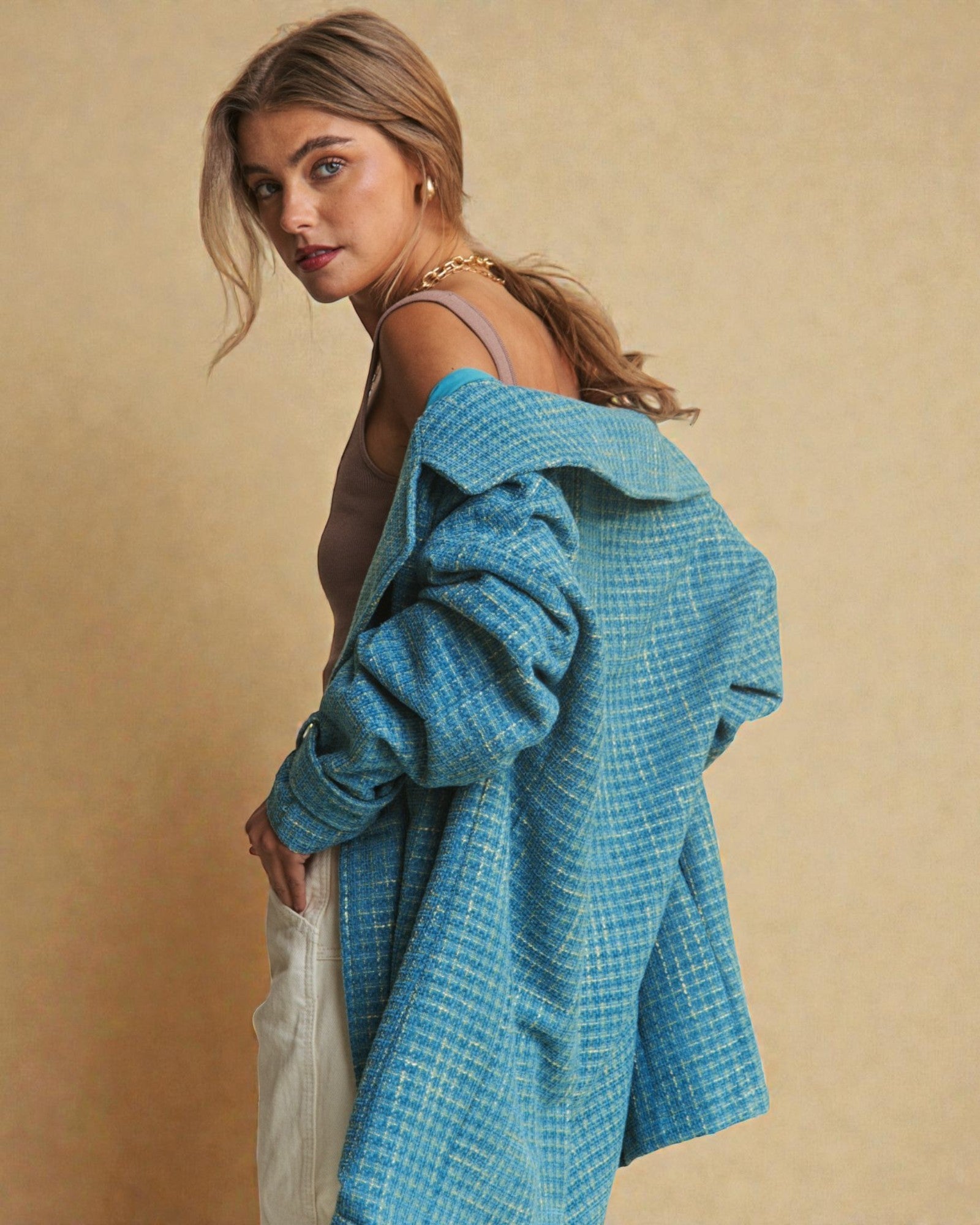Woman wearing a blue textured coat against a beige background